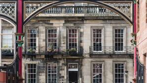A historic building with a prominent archway, multiple windows, and balconies with flower boxes.