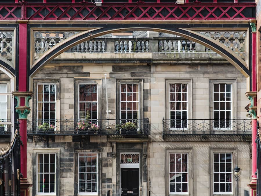 A historic building with a prominent archway, multiple windows, and balconies with flower boxes.