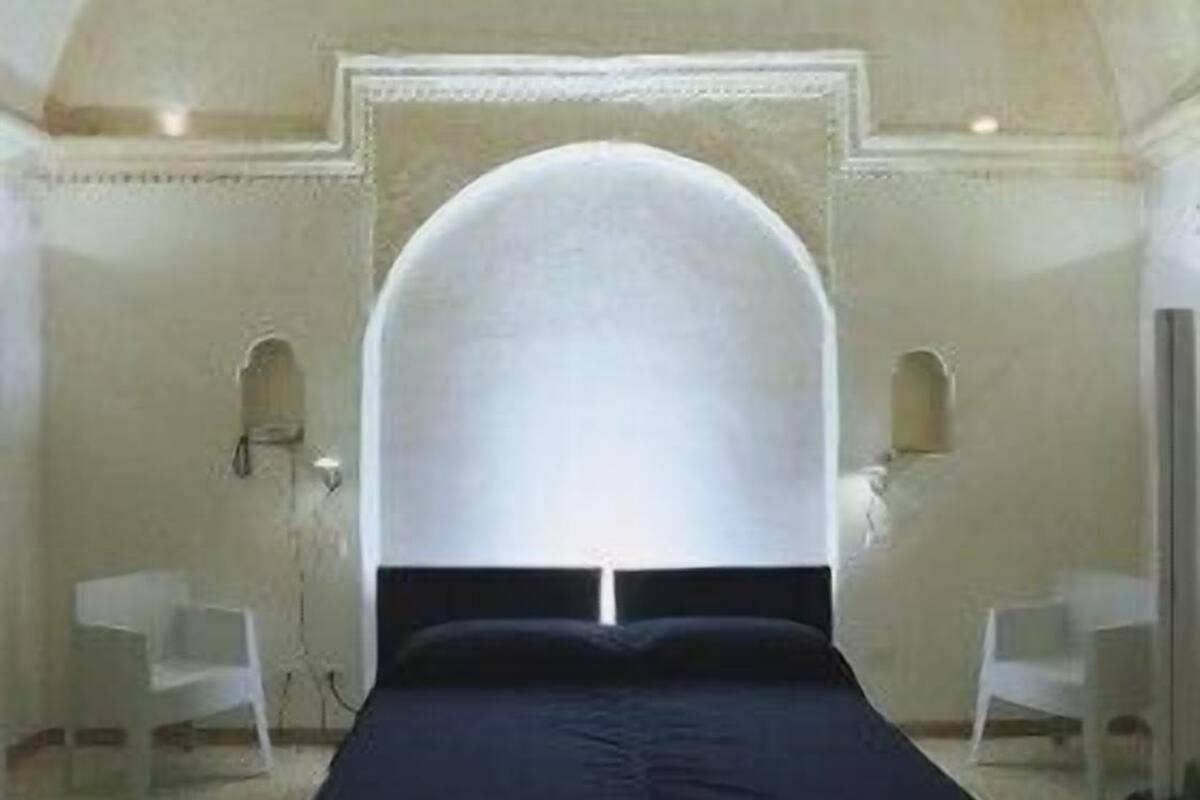 Un dormitorio con una cama grande, techo abovedado y dos mesitas de noche.