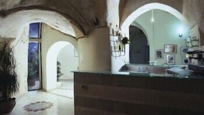 A rustic interior with arched ceilings, a central island with a sink, and a view through an archway.