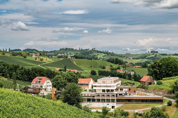 A modern building with multiple floors, surrounded by lush green vineyards and rolling hills. - Landgut am Pößnitzberg (Leutschach)
