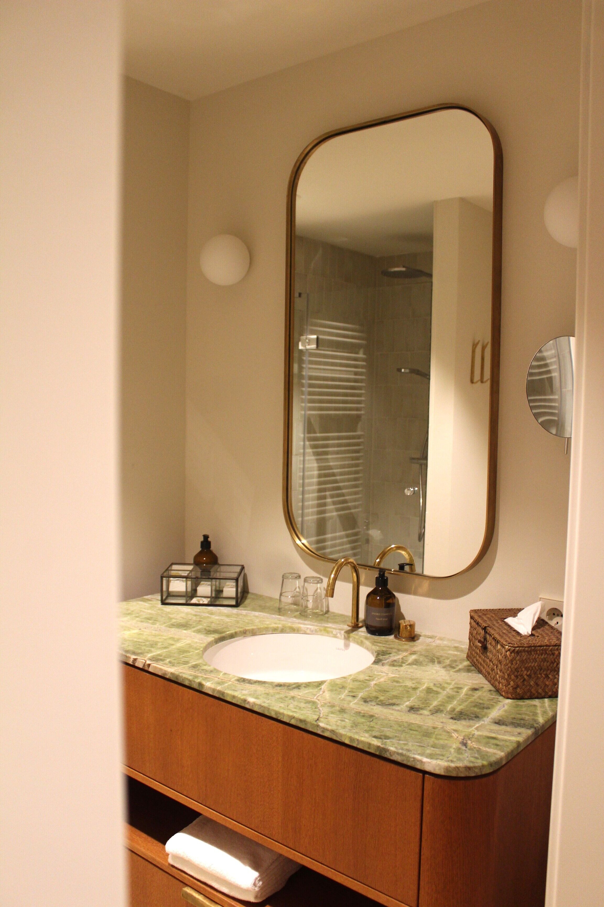 A bathroom with a green marble sink, a large mirror, and a towel rack.