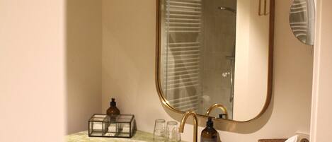 A bathroom with a green marble sink, a large mirror, and a towel rack.