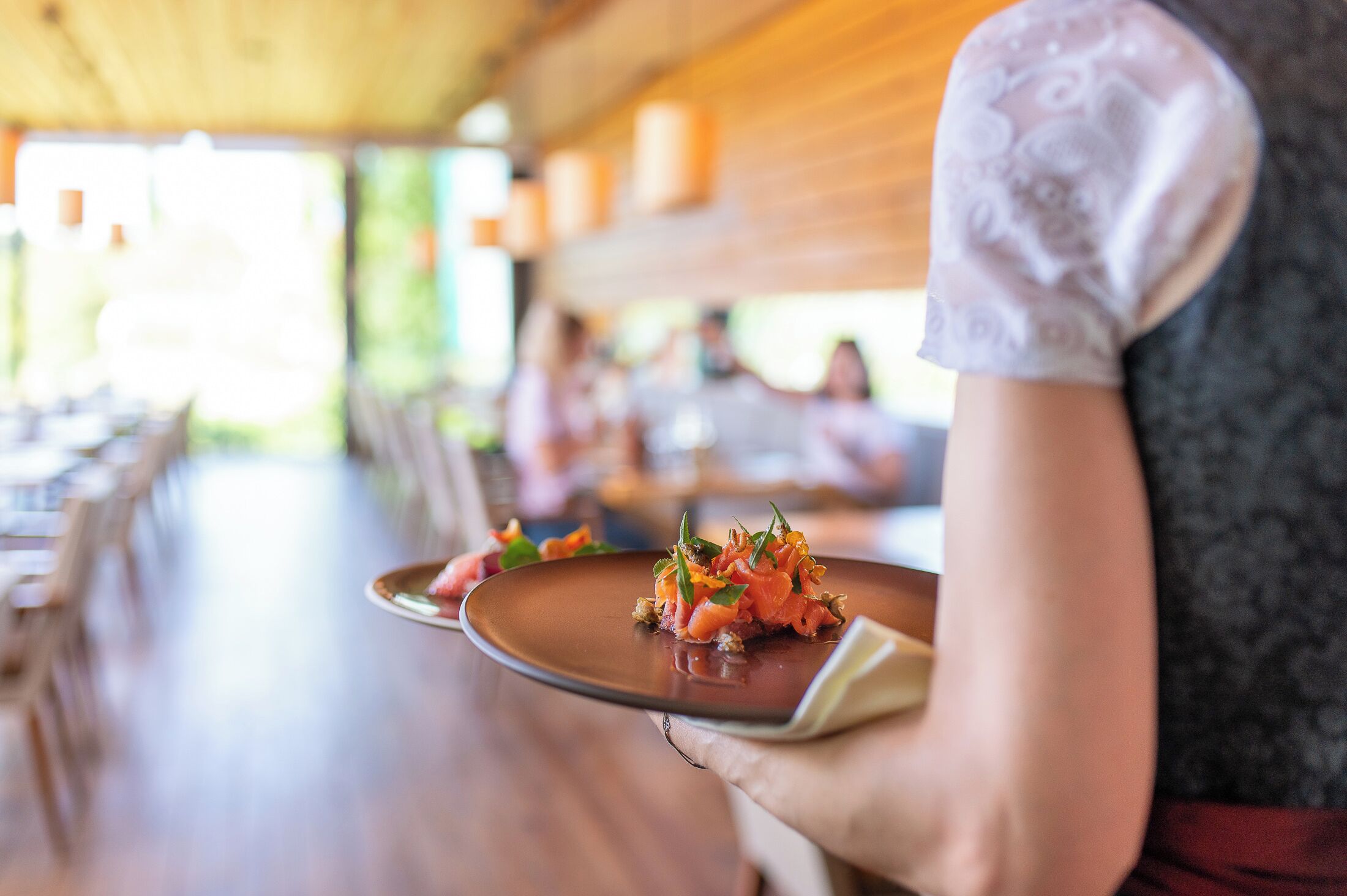 Een persoon houdt een bord eten vast in een restaurant.