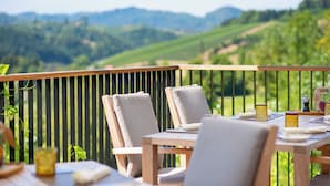 Una mesa de madera con sillas y vistas a un viñedo.