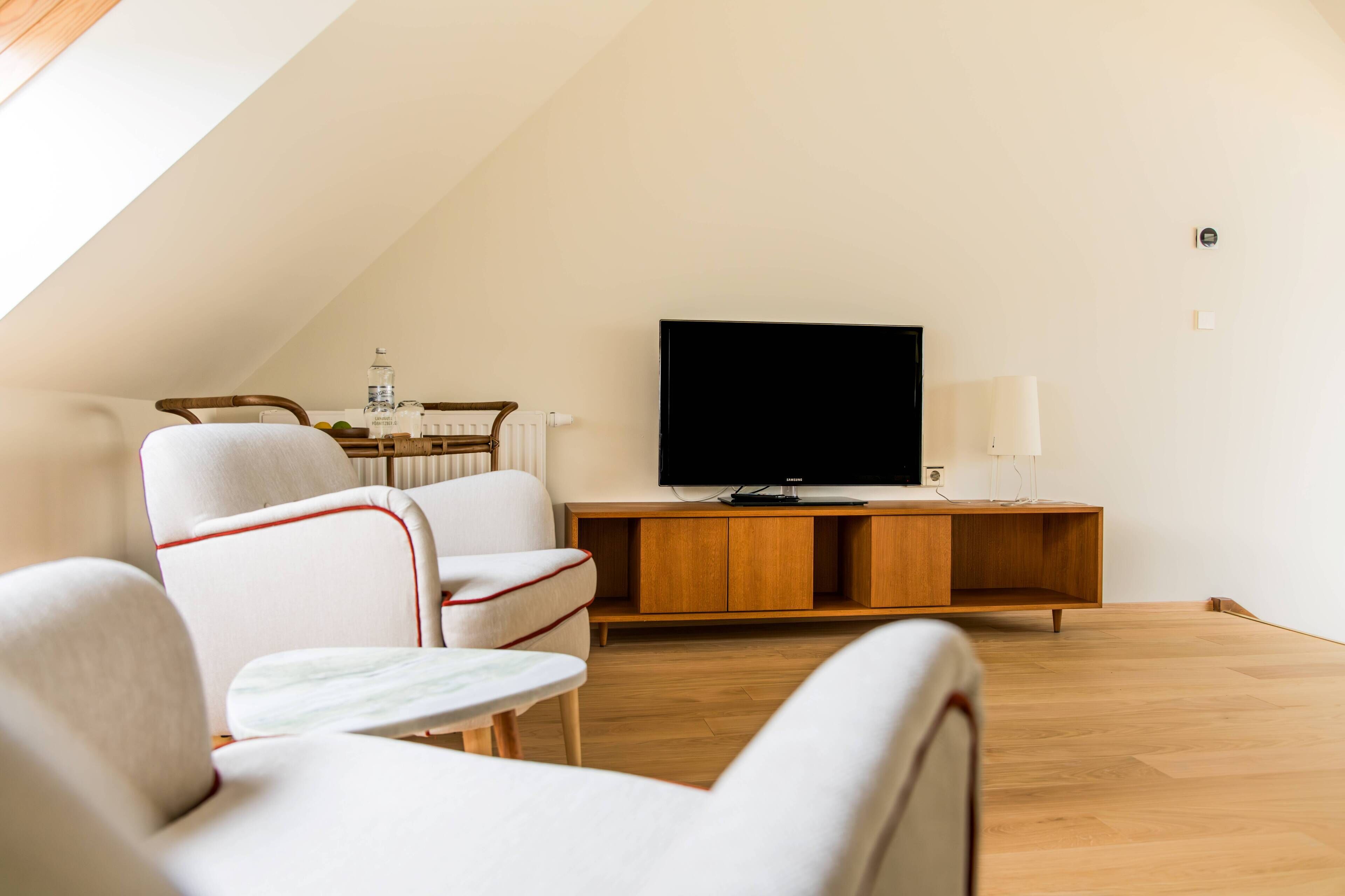 Un salon moderne avec un téléviseur à écran plat, des meubles en bois et une petite table.