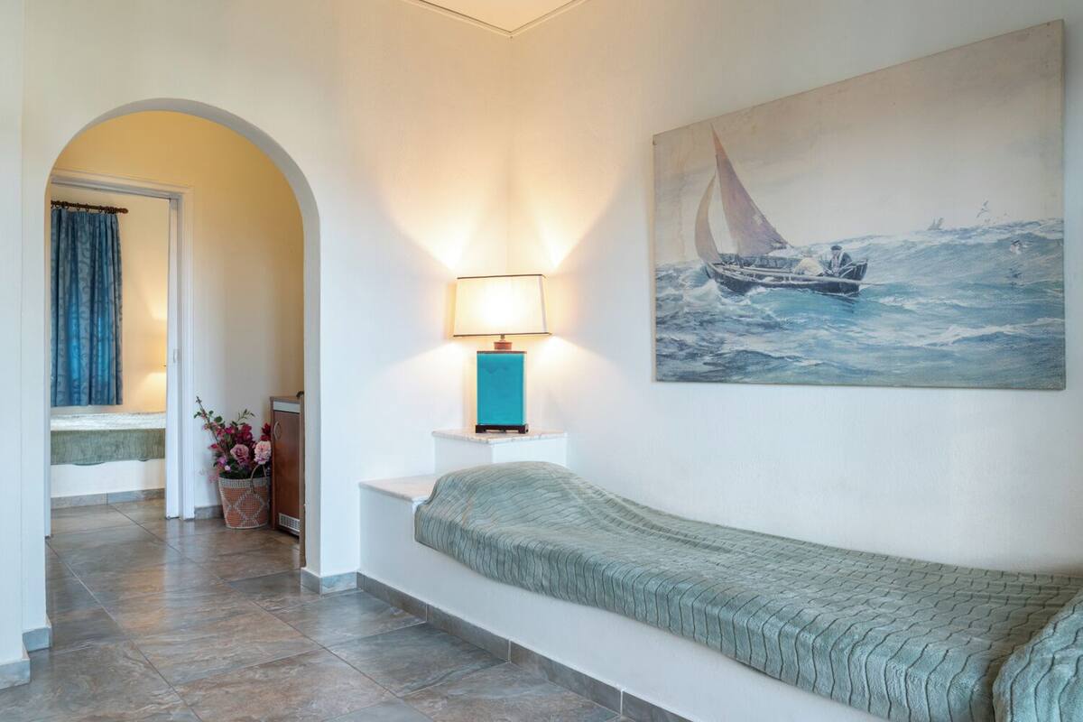 A hallway with a sofa, a lamp, a painting, and a potted plant.