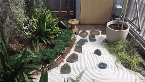 Un vialetto in giardino con un motivo in pietra, circondato da diverse piante e un vaso con una pianta.
