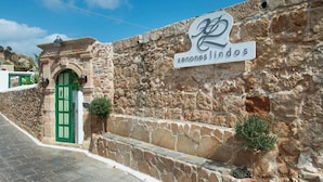 A stone building with a green door and a sign that reads "xenones lindos". - Xenones Lindos (Rhodes)