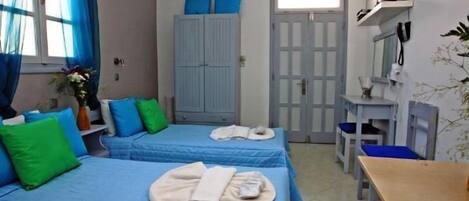 A room with two beds, a desk, a chair, a wardrobe, and a mirror.