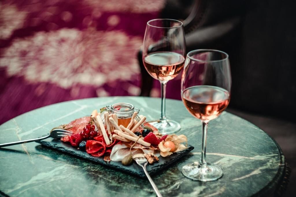 Una mesa con una tabla de pizarra, dos copas de vino y un tenedor.