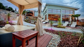 A modern outdoor lounge area with a wooden table, lounge chairs, and a canopy.