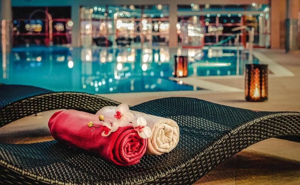 A poolside area with lounge chairs, a red and white towel, and a decorative candle.