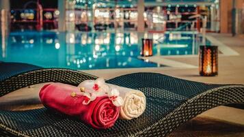 A poolside area with lounge chairs, a red and white towel, and a decorative candle.