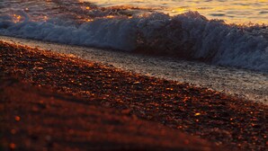 A beach with waves and a sunset. - Smaragdi Hotel (Santorini)