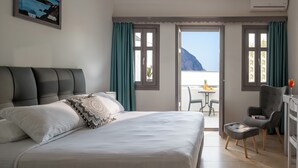A hotel room with a bed, a desk, and a balcony with a view of the sea. - Smaragdi Hotel (Santorini)