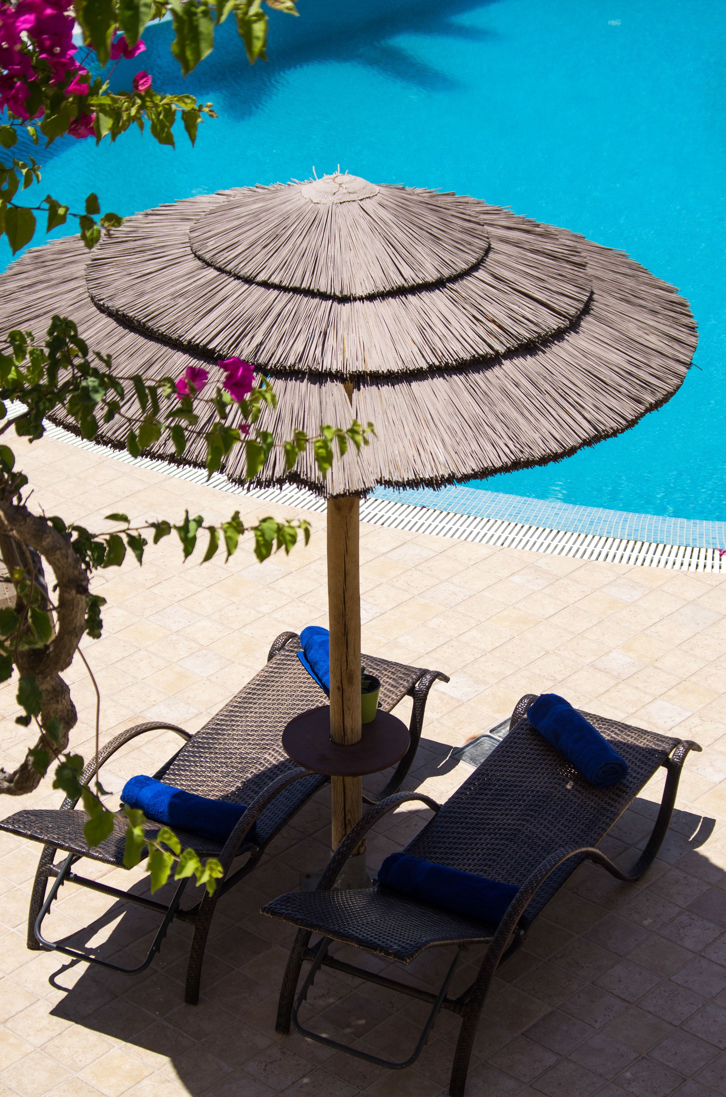 A poolside area with two lounge chairs and a large umbrella.