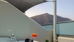 A hot tub with a mountain view, a drink, and a fruit basket. - Smaragdi Hotel (Santorini)