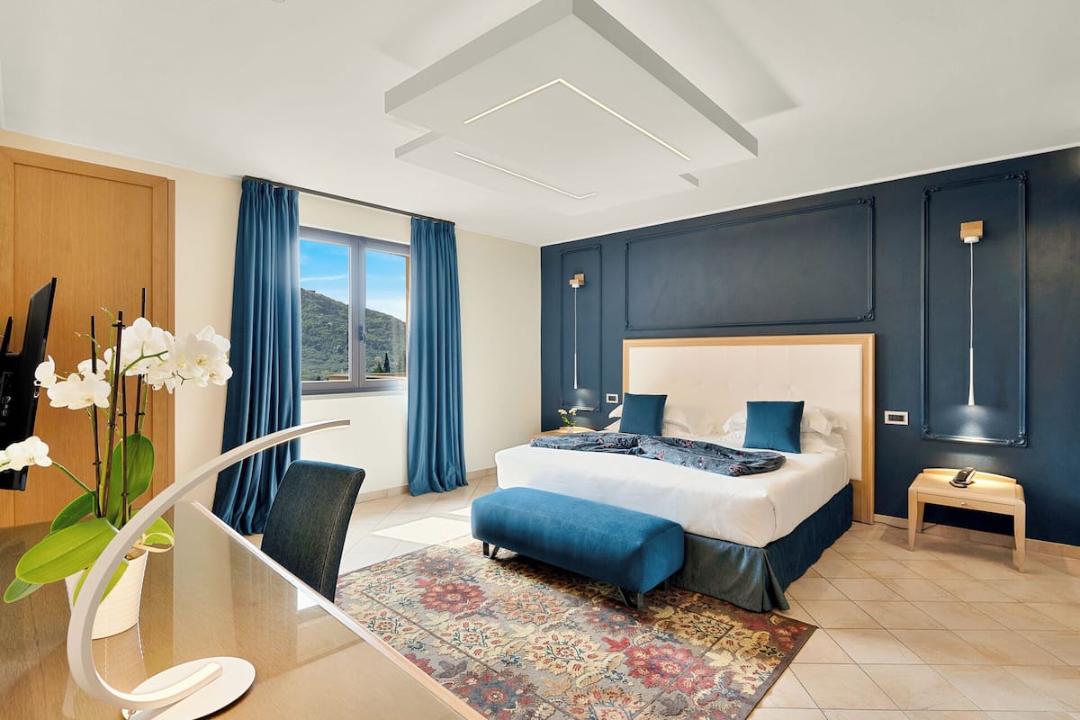 Une chambre d’hôtel moderne avec un grand lit, un bureau avec une chaise, une vue sur l’extérieur et un vase décoratif avec des fleurs.