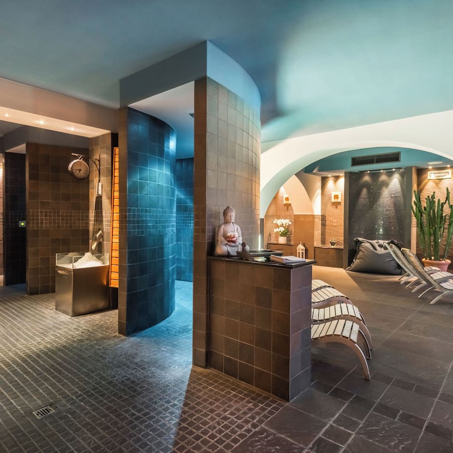 A modern spa area with a reception desk, seating area, and a large plant.