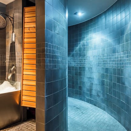 A bathroom with a sink, a clock, and blue-tiled walls.