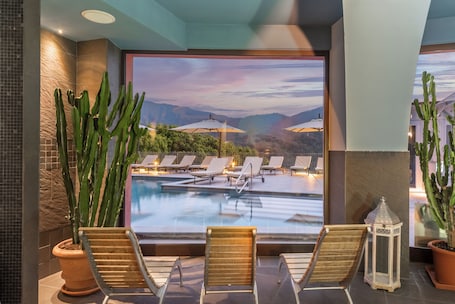 A poolside area with lounge chairs and a view of a mountainous landscape.