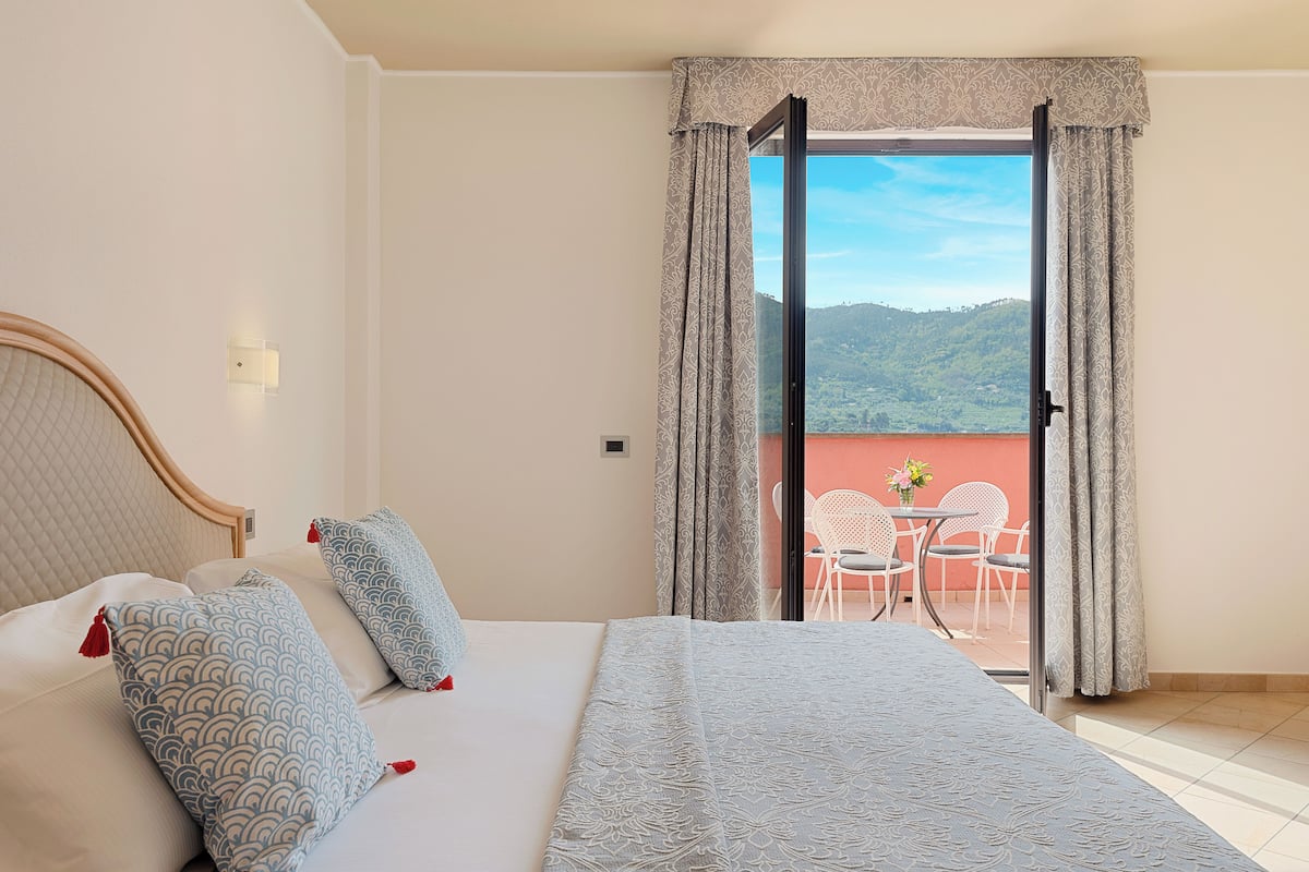 Une chambre à coucher avec un lit, des oreillers, une table de chevet et une fenêtre avec des rideaux.