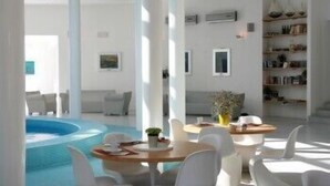 Un intérieur moderne avec une piscine, des meubles blancs et une bibliothèque.