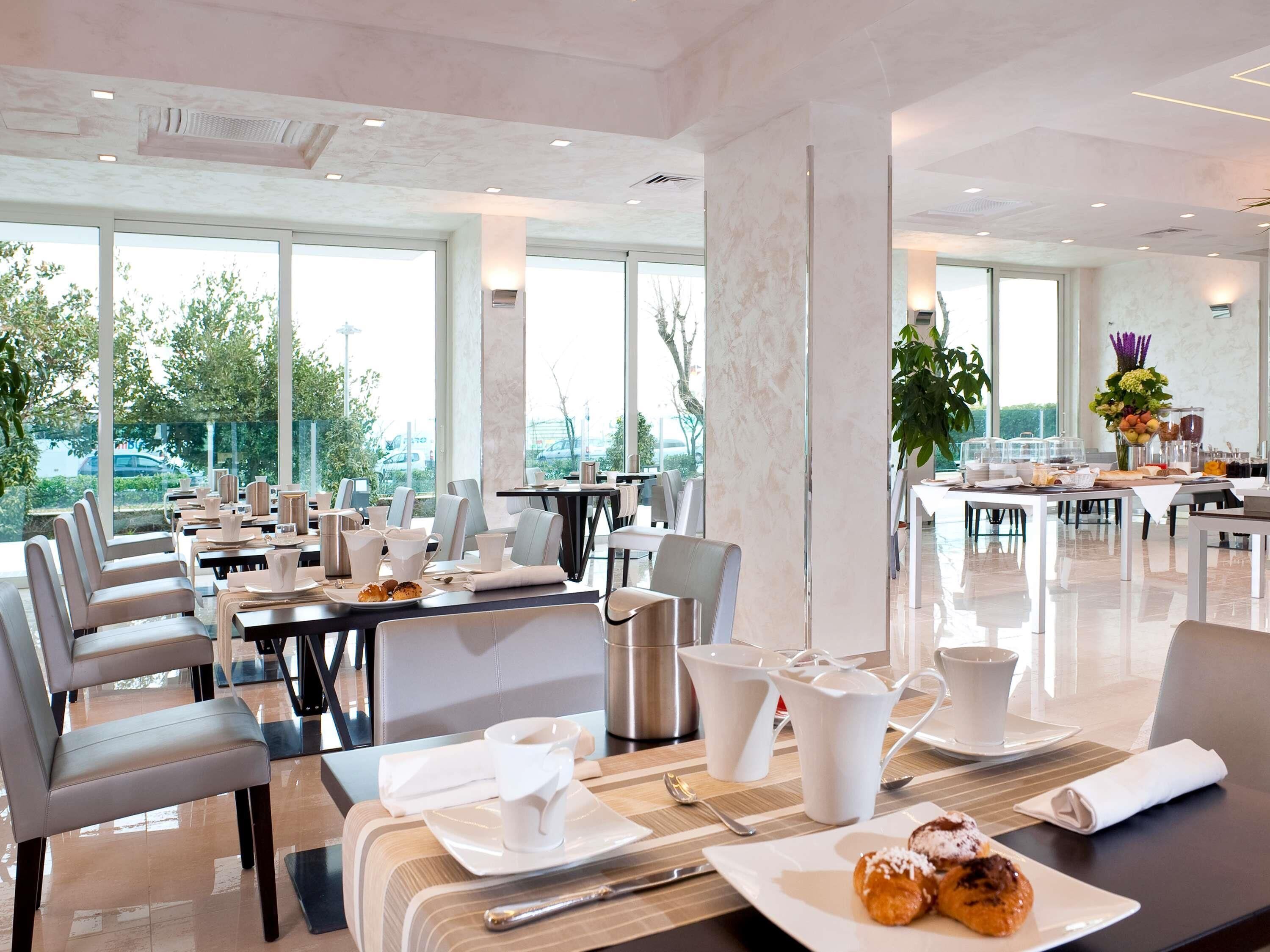 A modern dining area with tables, chairs, and a view of the outdoors.