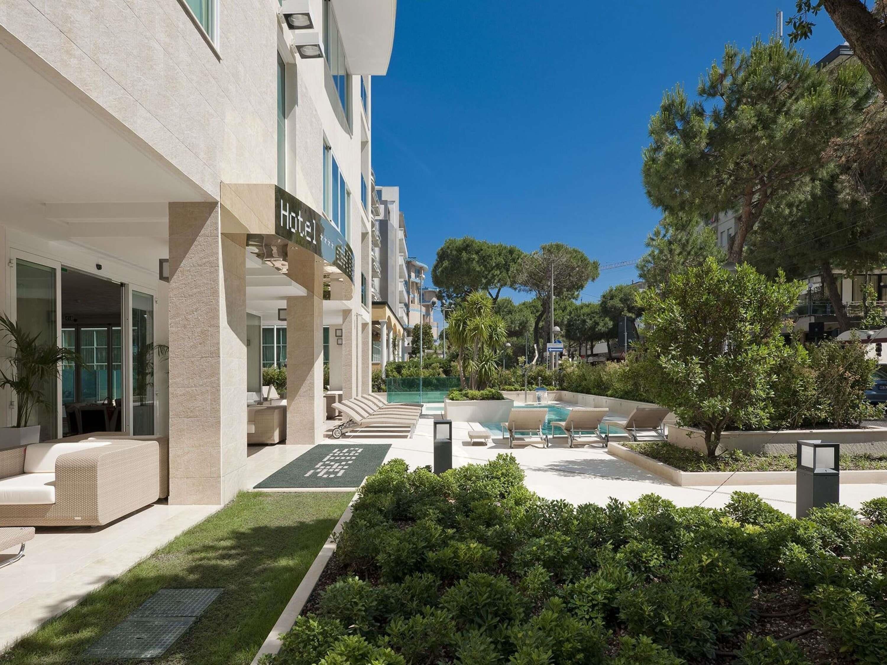 Un hotel con area piscina, posti a sedere all'aperto e vegetazione.