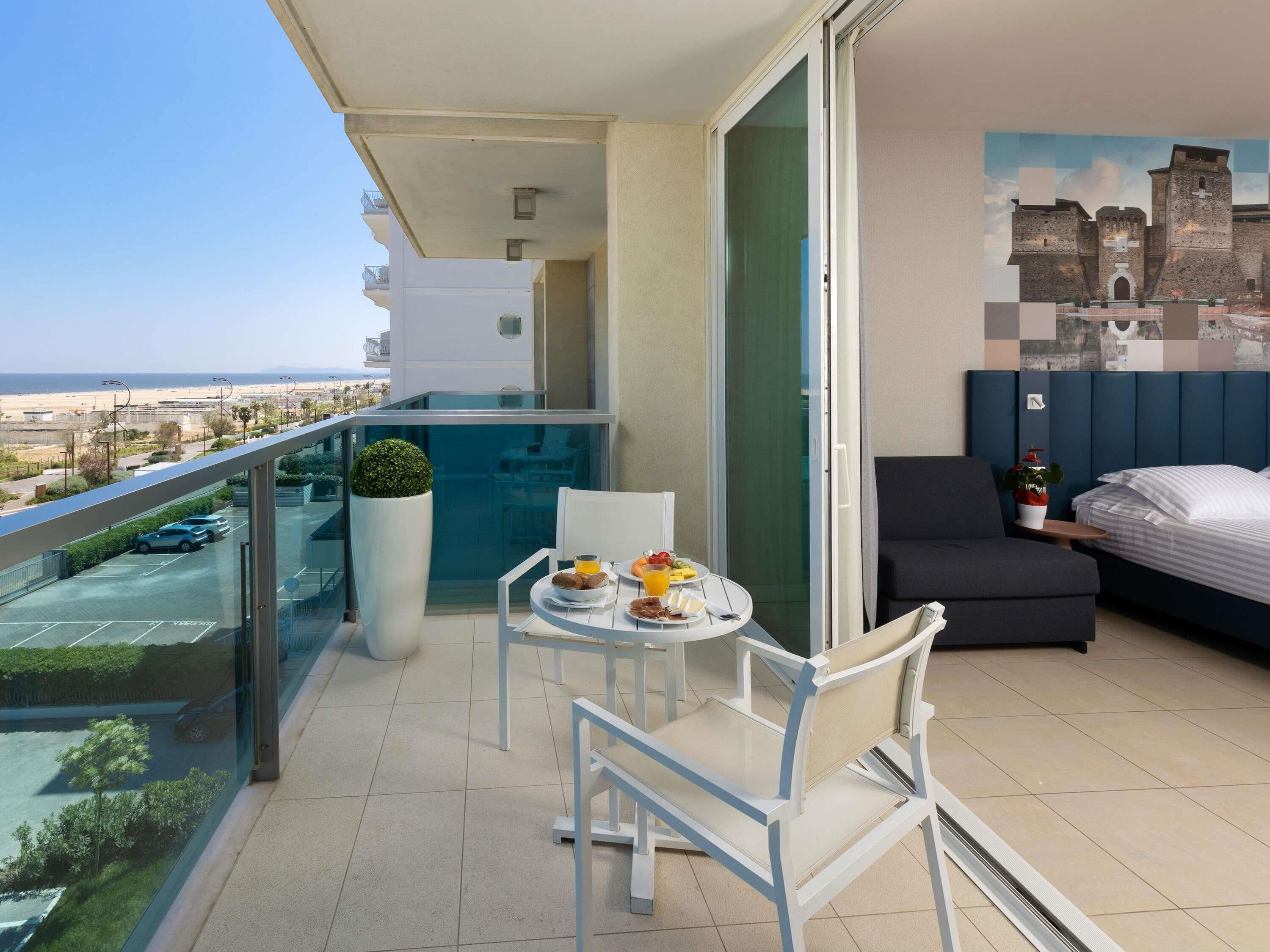 Ein Balkon mit Esstisch, Stühlen und Blick auf den Strand.