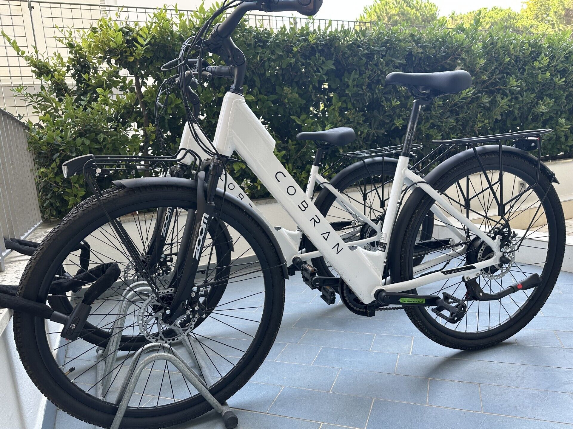 En hvid cykel med 'COBRAN' mærkning, bagagebærer og kurv foran.