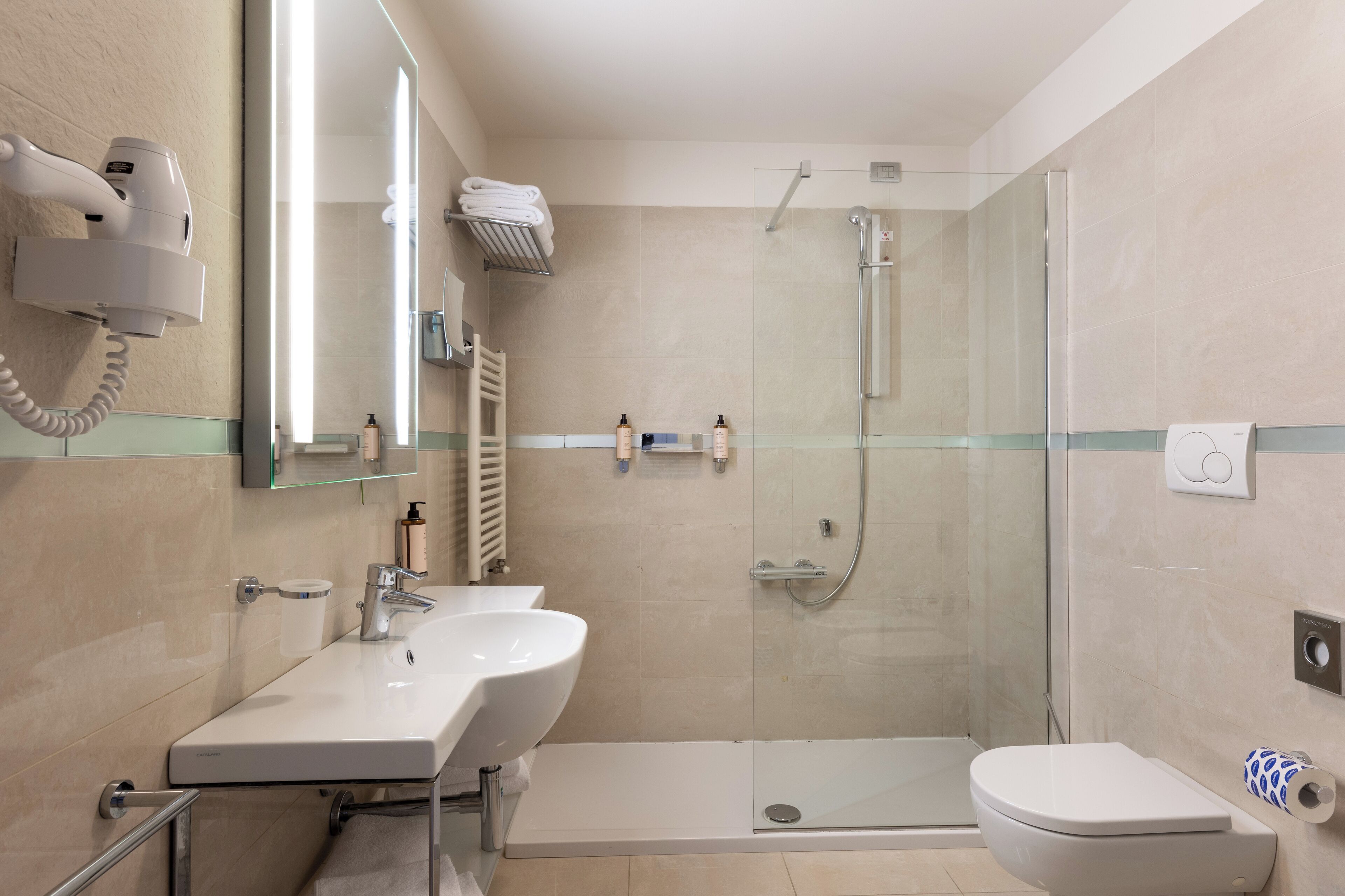 Un baño moderno con cabina de ducha de vidrio, un lavamanos blanco y un inodoro.