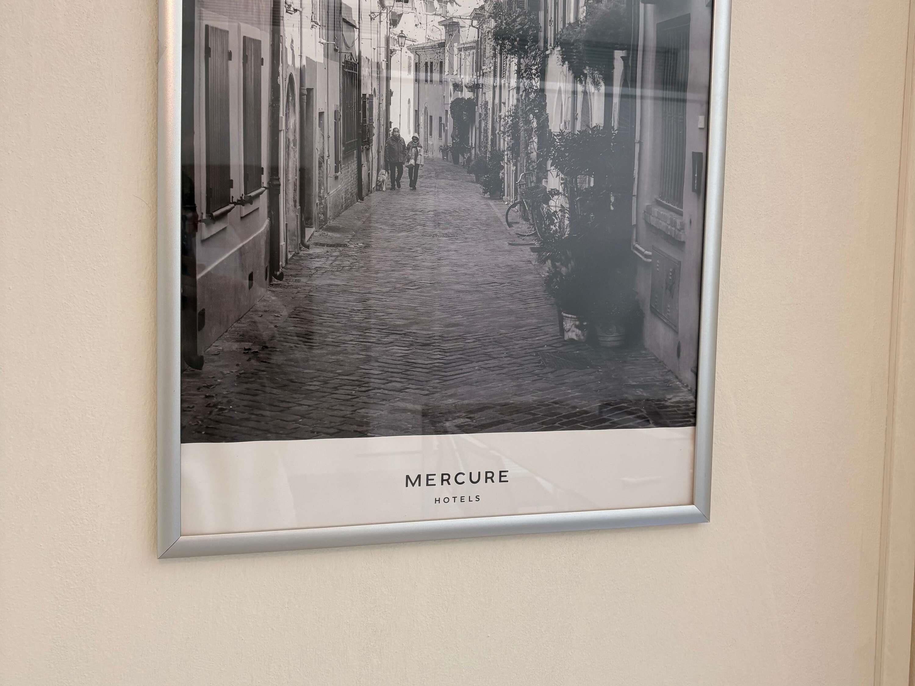 A framed photograph of a narrow cobblestone street with buildings on either side, labeled 'Mercure Hotels'.