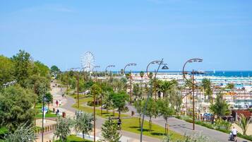 A coastal promenade with a Ferris wheel, palm trees, and a beach in the background.
