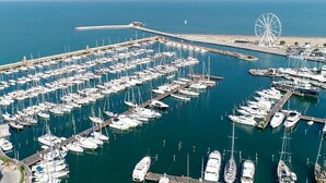 A marina with numerous boats docked, a large Ferris wheel, and a clear view of the ocean. - Mercure Rimini Artis (Rimini)