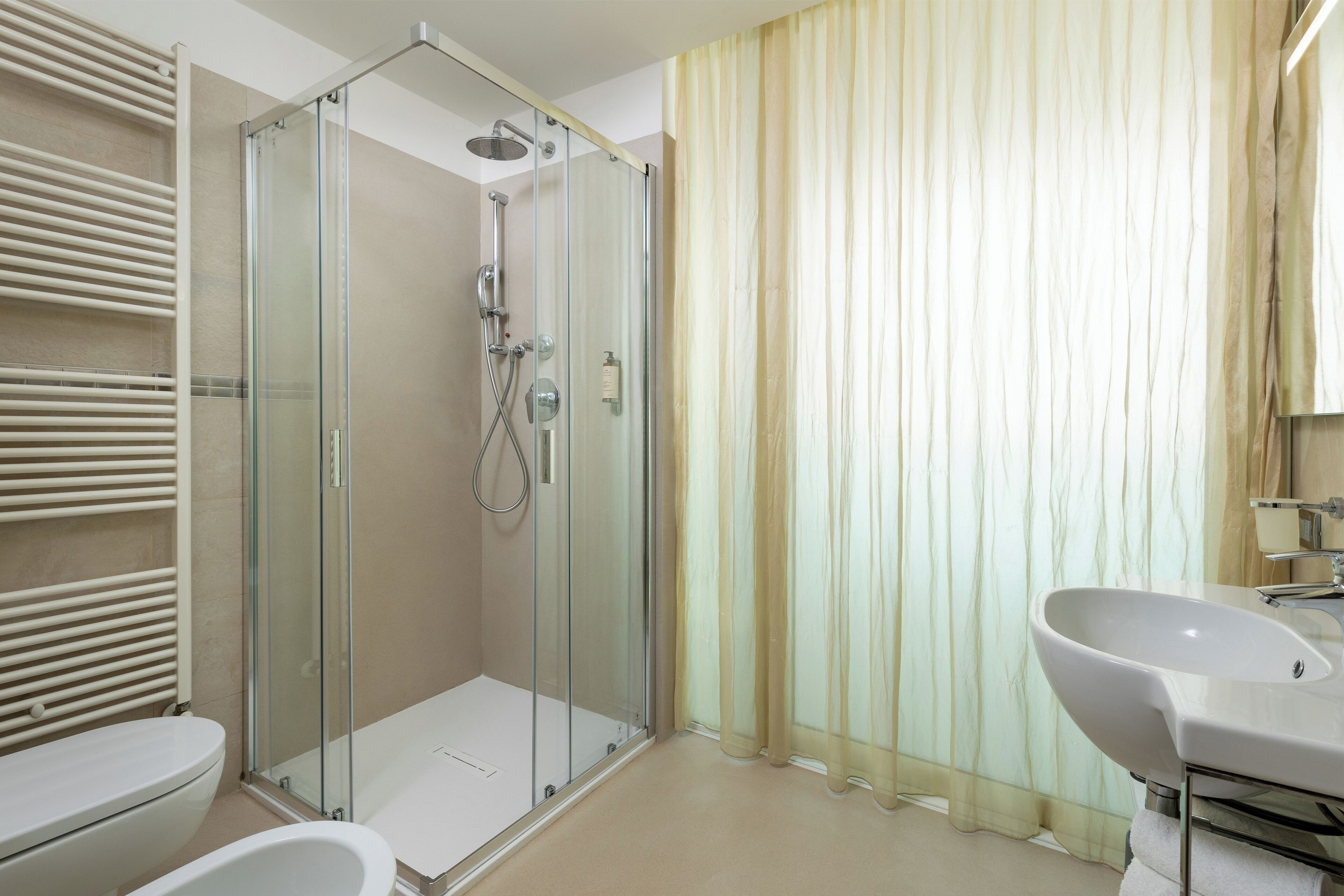 A modern bathroom with a glass-enclosed shower, a white sink, and a toilet.