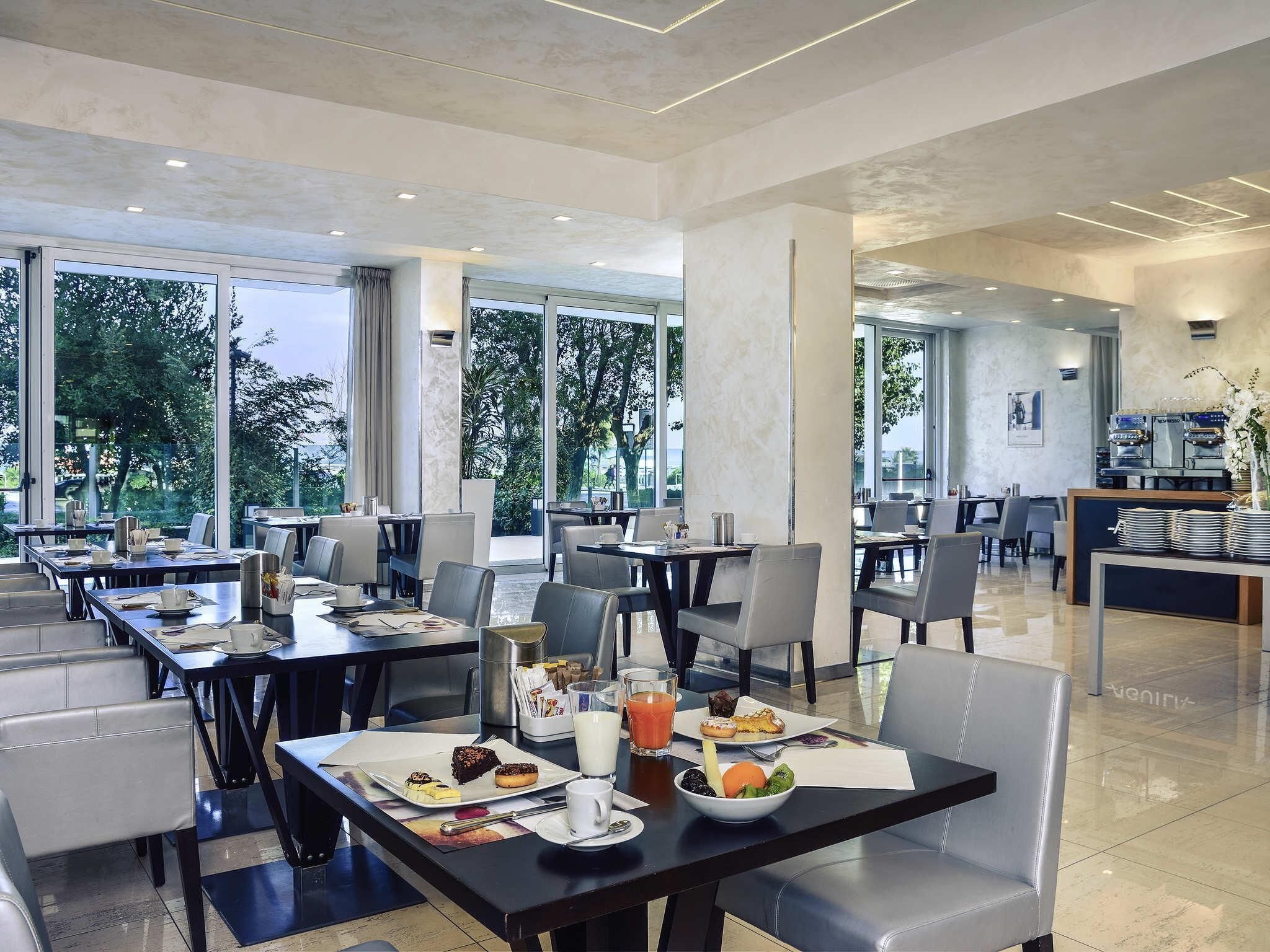 Un comedor moderno con mesas, sillas y una estación de buffet.