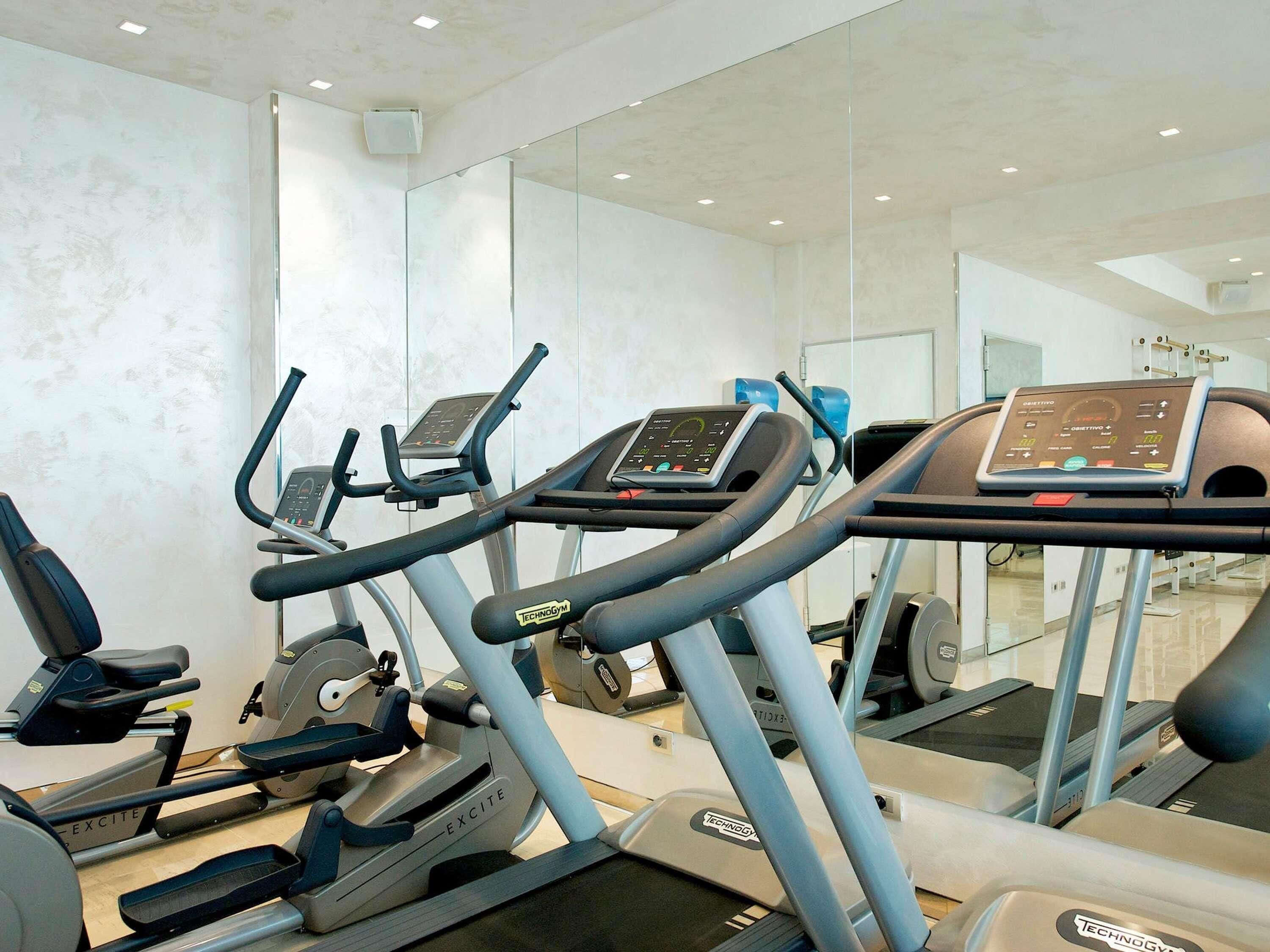 Un gimnasio con cintas de correr, elípticas y equipo de pesas.