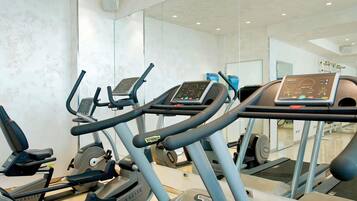 Un gimnasio con cintas de correr, elípticas y equipo de pesas.