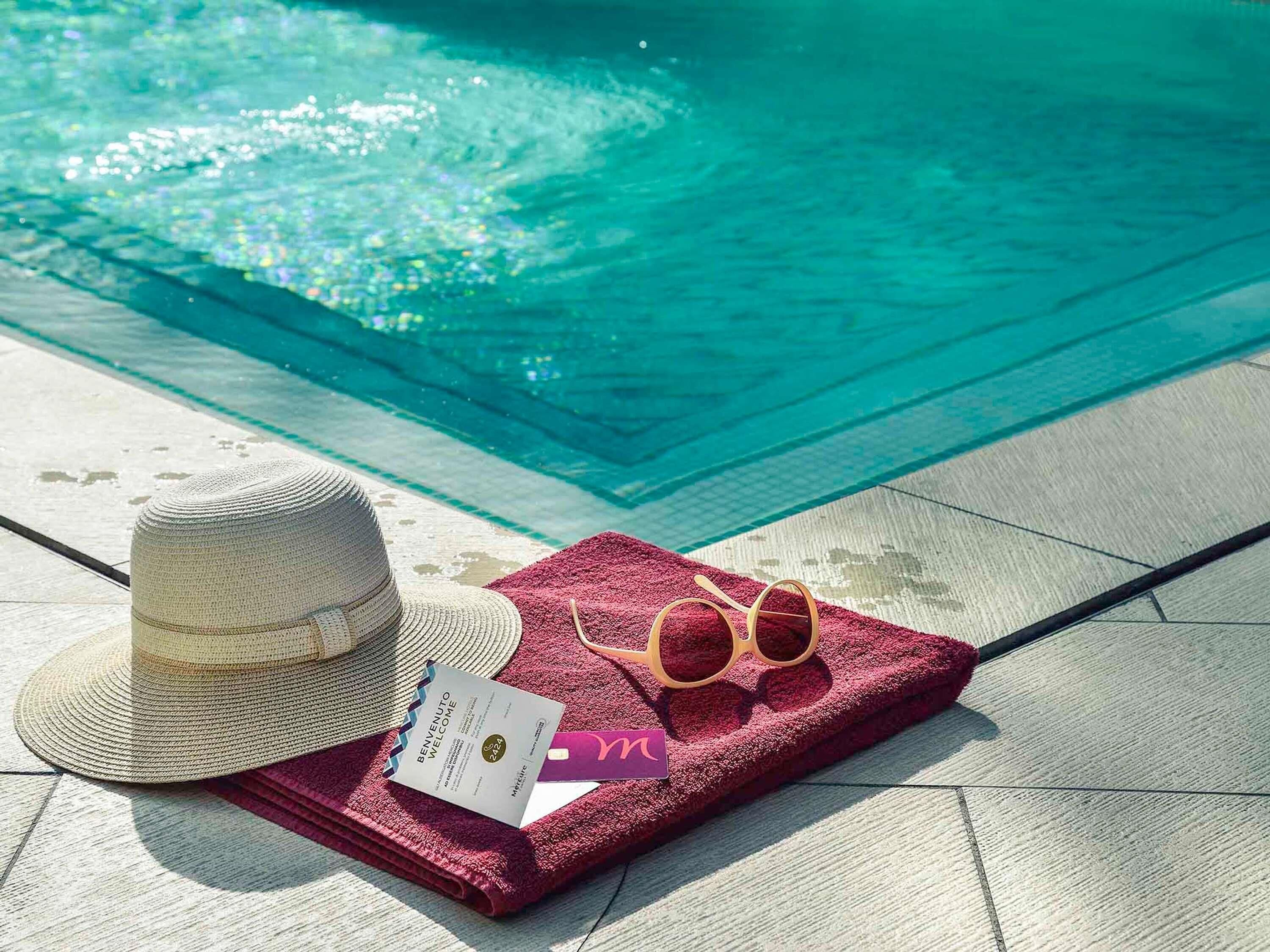 Escena junto a la piscina con un sombrero, gafas de sol y una tarjeta de bienvenida.