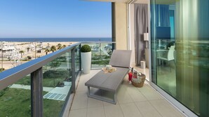 A balcony with a view of the beach, a lounge chair, a small table, and a potted plant. - Mercure Rimini Artis (Rimini)