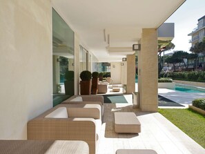 A modern outdoor lounge area with seating, a pool, and a view of the surrounding buildings. - Mercure Rimini Artis (Rimini)