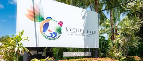 Une grande affiche publicitaire pour les appartements LYCHEE TREE, avec une pancarte indiquant « À LOUER » en dessous.