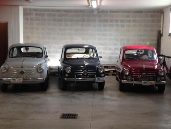 Tres autos antiguos estacionados en un garaje con pared de ladrillo.