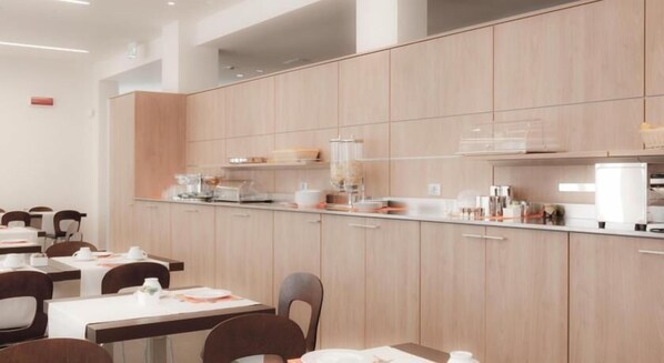 Un comedor de hotel moderno con armarios de madera clara, una barra larga y varias mesas con sillas.