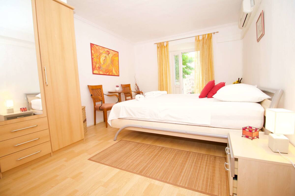 A bedroom with a bed, bedside table, chair, and wardrobe.