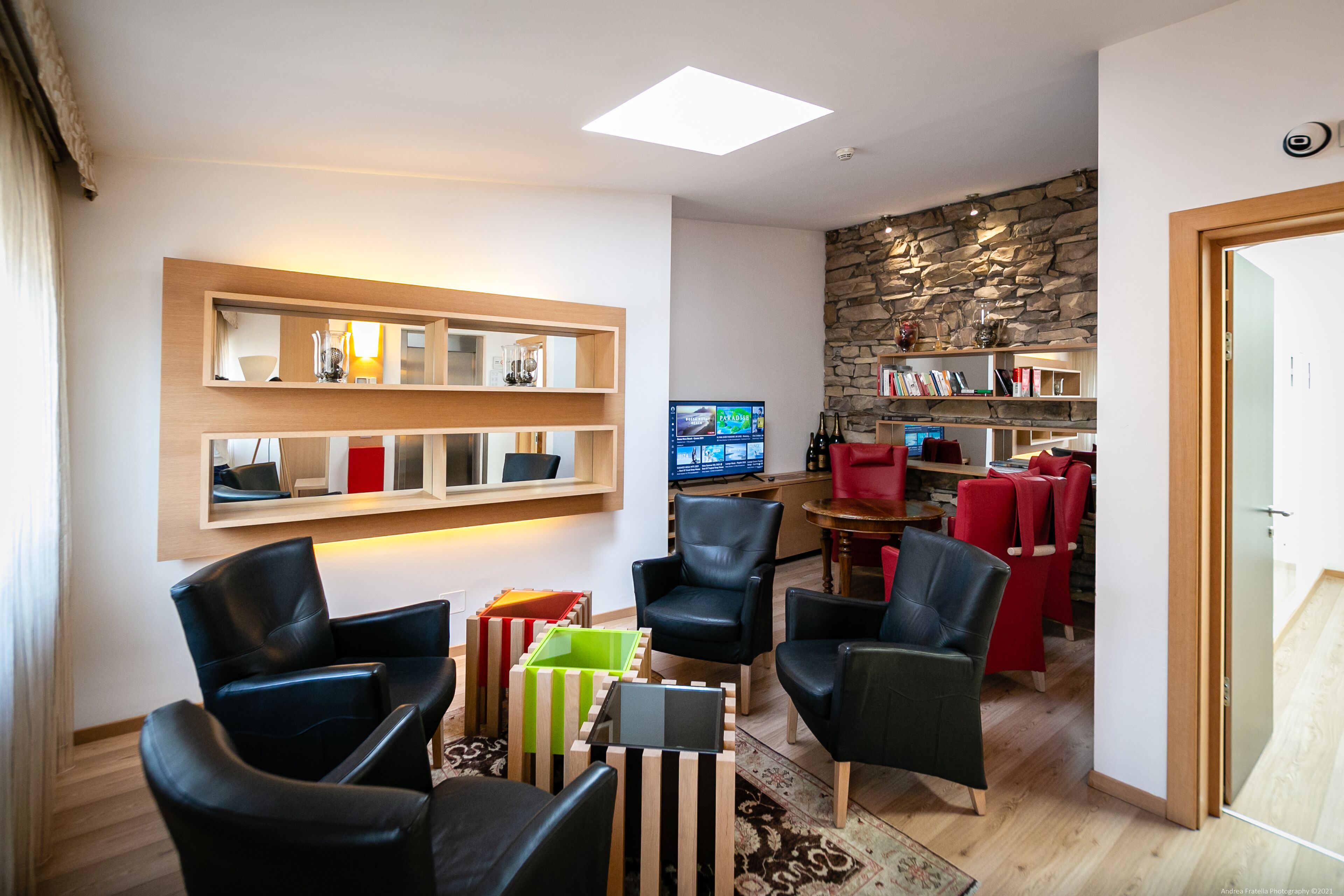 A modern living room with leather chairs, a TV, and a stone wall.