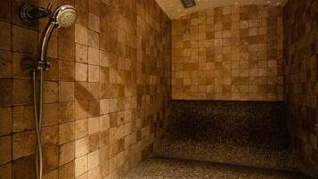 A tiled shower area with a showerhead and a vent.