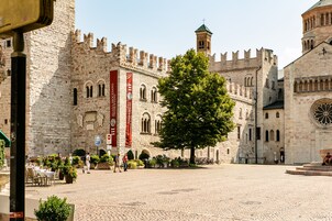 Un edificio histórico con un patio, muros de piedra y un árbol grande.